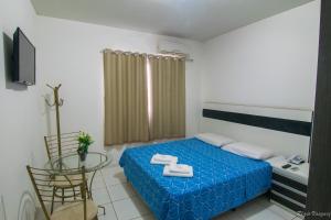 a bedroom with a blue bed and a table and chair at Hotel Caraipe in Teixeira de Freitas