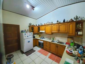 cocina con armarios de madera y nevera blanca en Sweet Mini Dortoir sur notre terrasse couverte pour vos transits entre deux vols by Kohutahia Lodge, 7 min by car to airport and town en Faaa