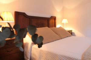 1 dormitorio con 1 cama con sábanas blancas y 2 lámparas en La casa de Dona Lucila, en Cambados