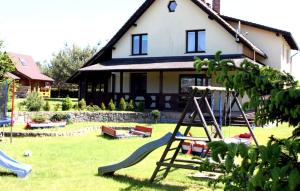 a house with a playground in the yard at Leniuchowo in Junoszyno
