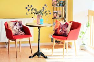 dos sillas y una mesa con una almohada de dos gatos en La chambre aux hirondelles, en Ittenheim