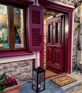 una puerta roja y un taburete negro delante de una casa en Pension Anapli, en Nauplia