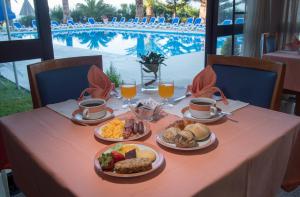 einen Tisch mit Teller mit Lebensmitteln und Gläsern Orangensaft in der Unterkunft Hotel Sao Jorge Garden in Velas