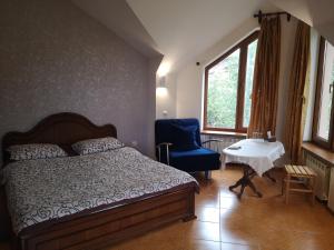 ein Schlafzimmer mit einem Bett, einem Stuhl und einem Tisch in der Unterkunft Hotel Edem in Zaghkadsor
