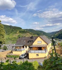 a yellow house with a car parked in front of it at Die Ferienwohnung Lindenhof in Zell an der Mosel