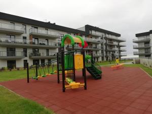 un parque infantil frente a un edificio de apartamentos en GARDENIA Apartament Przy Plaży 19, en Dziwnów