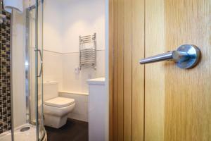 een badkamer met een toilet en een glazen deur bij Beach Front Guest House in Eastbourne