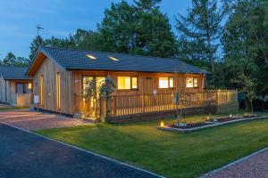 a small cabin with a fence and a yard at Settlers Lodge in Otterburn