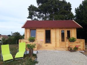 a log cabin with two green chairs in front of it at Chalet de Fred in Saint-Ouen-de-Mimbré