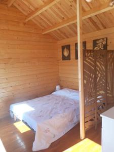 a bedroom with a bed in a wooden cabin at Chalet de fred in Saint-Ouen-de-Mimbré