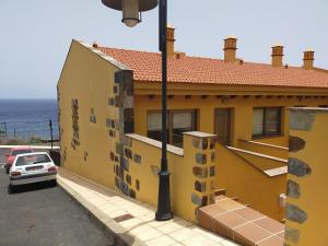 ein gelbes Haus mit einem Auto auf einem Parkplatz in der Unterkunft NAUTILUS II in La Caleta