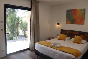 a bedroom with a large bed and a sliding glass door at Hôtel Padolo in Bonifacio