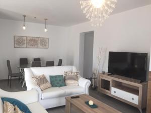 a living room with a white couch and a flat screen tv at Villas Santa Ana in Conil de la Frontera