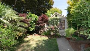 a small white house with a garden of plants at San Jose Cottage in Victoria