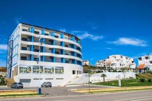 a large white building with cars parked in a parking lot at Studio avec piscine Cabo Dream à Cabo négro in Cabo Negro
