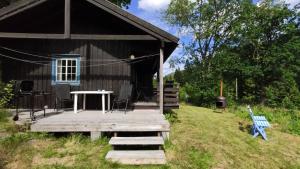 a cabin with a wooden deck and a table and a chair at Solheim. Hytte med 2 soverom in Birkenes