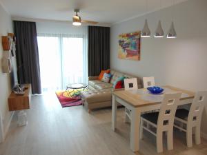 una sala de estar con una mesa y un sofá en GARDENIA Apartament Przy Plaży 19, en Dziwnów
