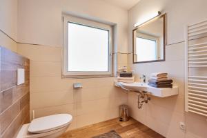 ein Badezimmer mit Toilette und Waschbecken und einem Fenster in der Unterkunft Bergfink apartments in Flachau + 19 Fotos