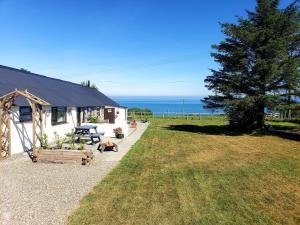 a white house with a picnic table and a tree at Byre Cottages & Log Cabin in Cardigan