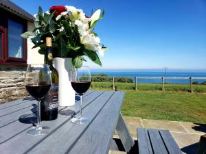 une table avec deux verres de vin et un vase de fleurs dans l'établissement Byre Cottages & Log Cabin, à Cardigan