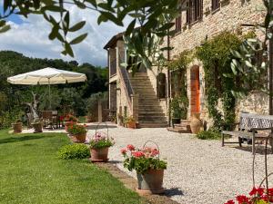 un jardín con macetas y sombrilla y un edificio en Casa delle Sorgenti, en Montefiore dellʼAso