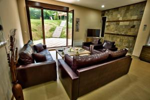 a living room with leather couches and a table at Holiday Home Marta in Dobrevtsi