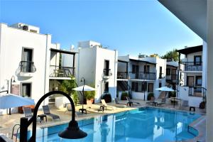 a pool with chairs and umbrellas in front of buildings at Modern Life Hotel Bodrum in Gümbet