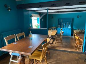 uma sala de jantar com paredes azuis e mesas e cadeiras de madeira em The Benett Arms em Shaftesbury