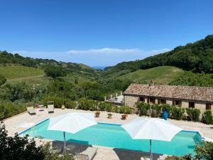 una vista exterior de una casa con piscina y sombrillas en Casa delle Sorgenti, en Montefiore dellʼAso