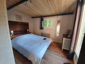 a bedroom with a large bed with a wooden ceiling at Le lodge sur pilotis in Fichous-Riumayou