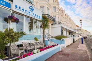 a beach front building with benches and flowers on a street at Beach Front Guest House in Eastbourne