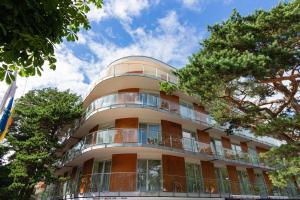 a tall building with a balcony and trees at Amber apartment in Palanga