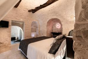 a bedroom with a bed in a stone wall at DIMORA RITUNNO in Locorotondo