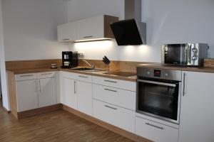 a kitchen with white cabinets and a sink and a microwave at Luxuriöse Stadtwohnungen in Königstein in Königstein an der Elbe