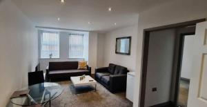 a living room with two couches and a glass table at Cosy Executive City Apartment in Doncaster