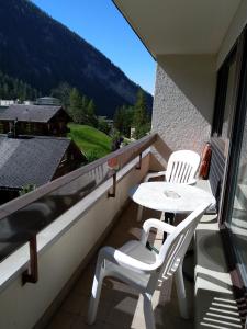 einen Balkon mit zwei weißen Stühlen und einem Tisch in der Unterkunft Fortuna 404 in Leukerbad
