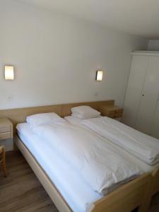 ein großes weißes Bett in einem Zimmer mit zwei Lichtern in der Unterkunft Fortuna 404 in Leukerbad