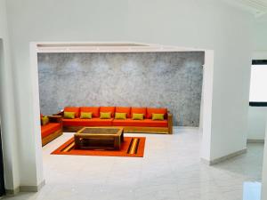 a living room with an orange couch and a table at Quatre appartements en location a Saly-Senegal in Saly Portudal