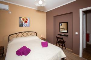 - une chambre avec un lit et des serviettes pourpres dans l'établissement G and A House, à Poros