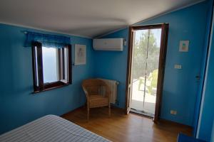 a bedroom with blue walls and a chair and a window at Il Sole di Valletonda Holiday House in Corniglia