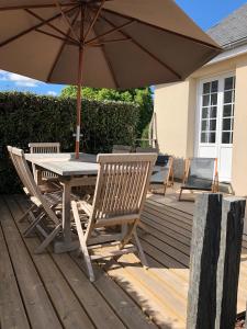 una mesa y sillas con una sombrilla en la cubierta en Les terrasses ensoleillées de Carteret en Barneville-Carteret