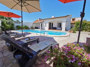 una piscina con 2 sillas y una sombrilla en La Casa del Arti - Chambres d'hôtes, en Sigean