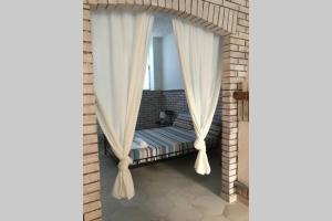 a bed in a brick room with curtains at Lake It Easy Mandello in Mandello del Lario