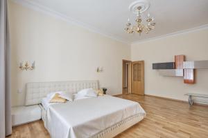 - une chambre blanche avec un grand lit et un lustre dans l'établissement Villa Deluxe Apartments, à Karlovy Vary