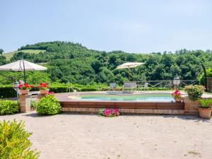 a swimming pool with a deck and flowers and umbrellas at Belvilla by OYO Villa Angolo Fiorito in Urbino