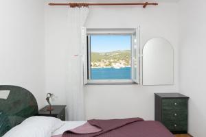 1 dormitorio con cama y ventana en Apartments Babin, en Vinišće