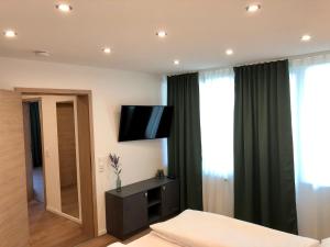 a bedroom with a bed and a flat screen tv at City Apartments in Metzingen