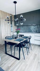 a dining room table with chairs and a kitchen at Apart House by Gardenia in Dziwnów
