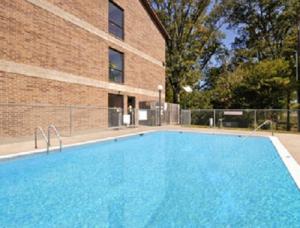 duży niebieski basen obok ceglanego budynku w obiekcie Super 8 by Wyndham Kennett w mieście Kennett