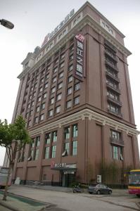 a large hotel building with a car parked in front of it at Jinjiang Inn - Shanghai Songjiang University Town in Songjiang